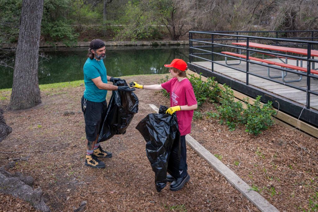 Two people picking up trash near picnic benches in Koehler Pavilion