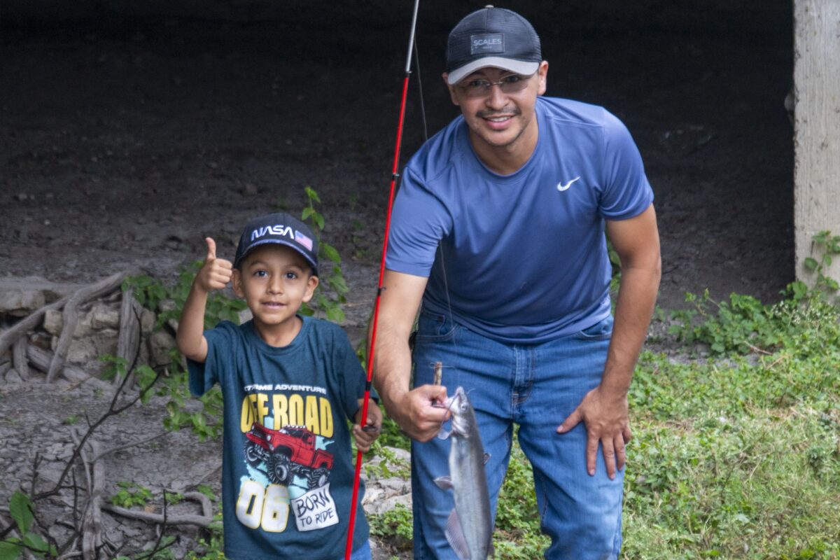 Father holding a fish that he caught with his son.