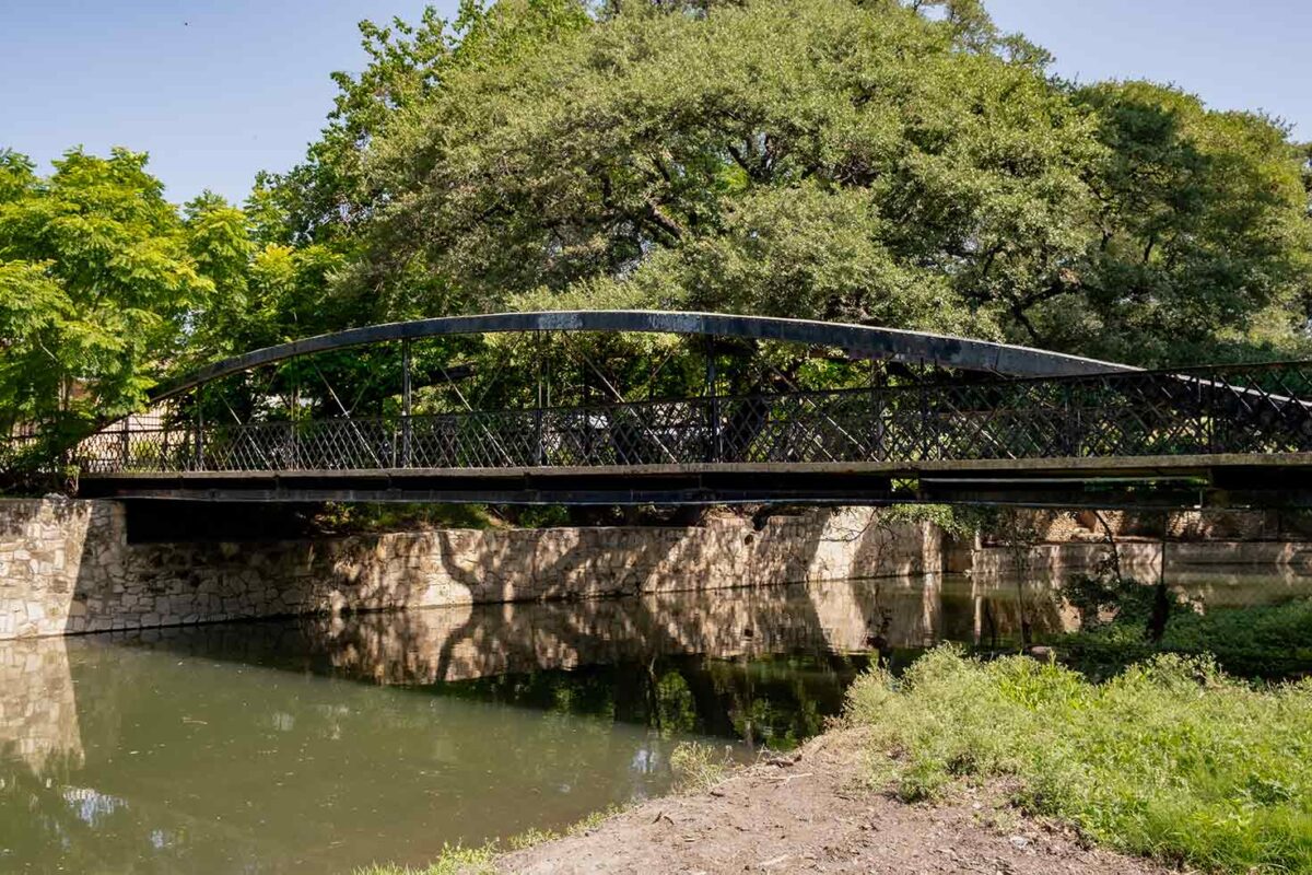 Pedestrian Bridge with trees in the background and river underneath bridge