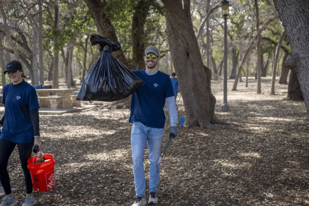 Volunteers picking up trash in beautiful wooded area of park.