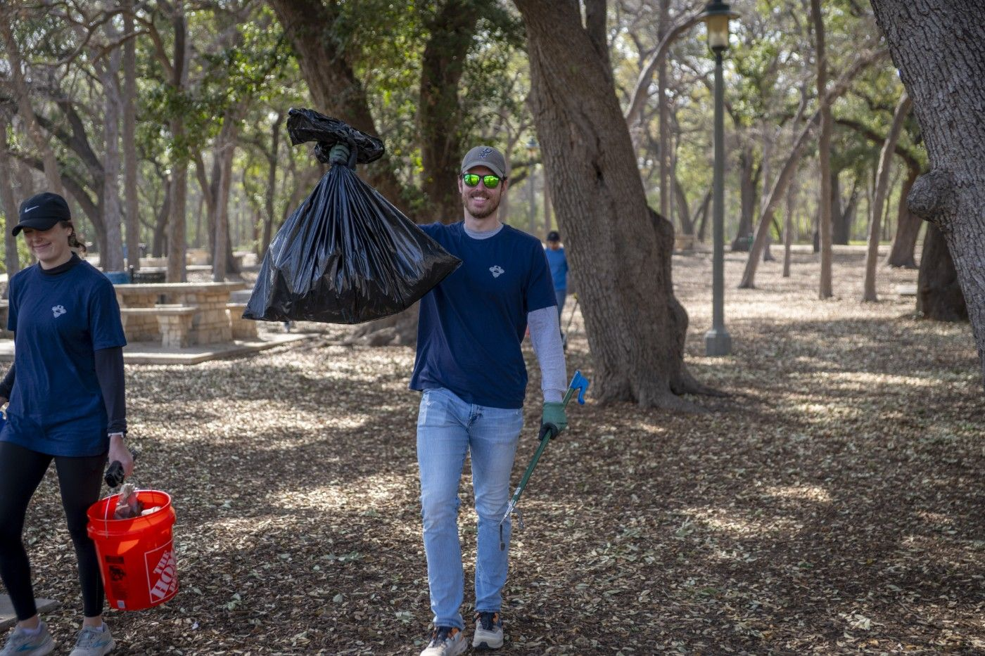Volunteers picking up trash in beautiful wooded area of park.