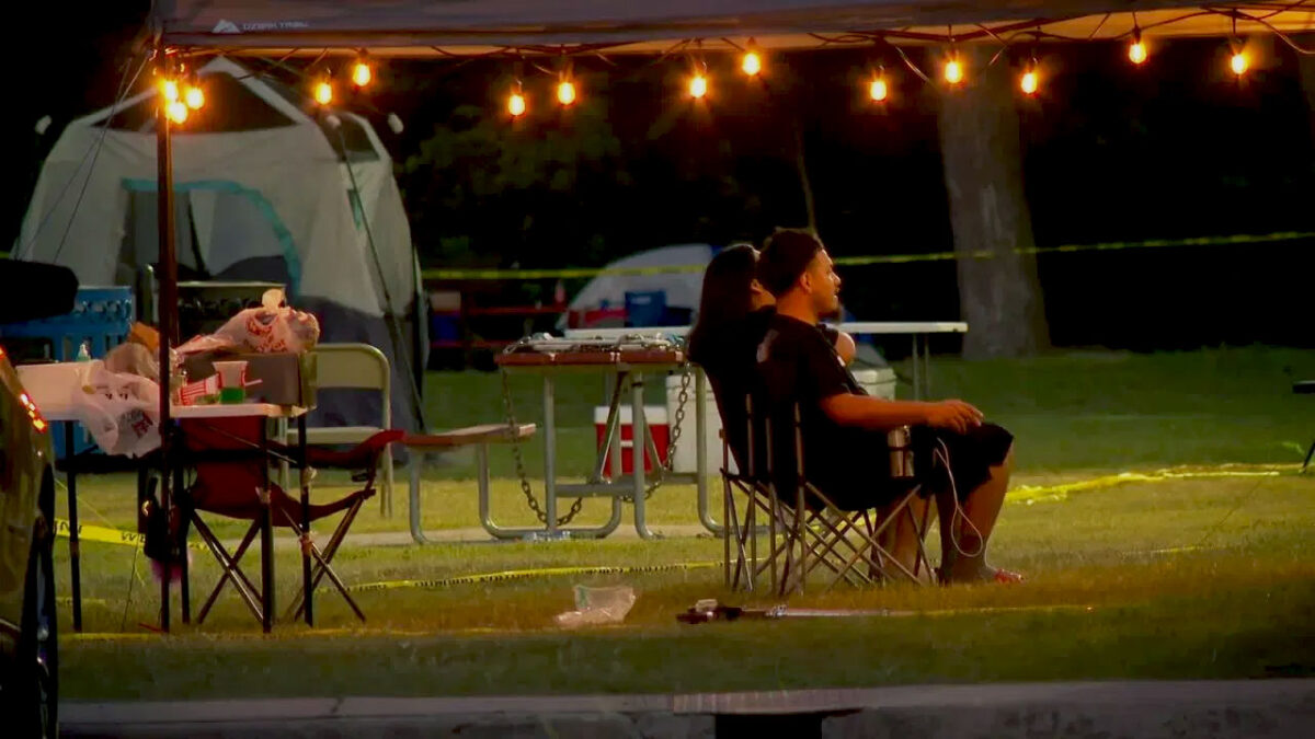 Two campers sitting in lawn chairs at night time